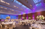 white flower centerpieces on white dining tables in a large venue