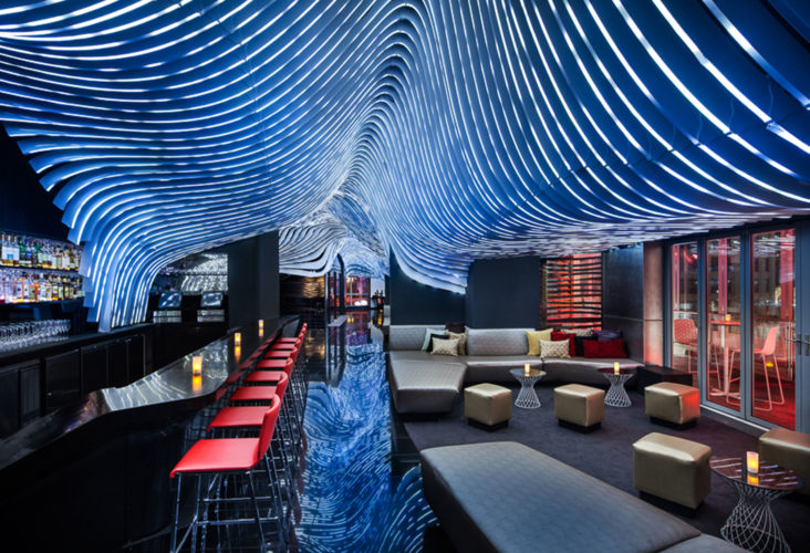 bar and lounge area with abstract line art on the ceiling